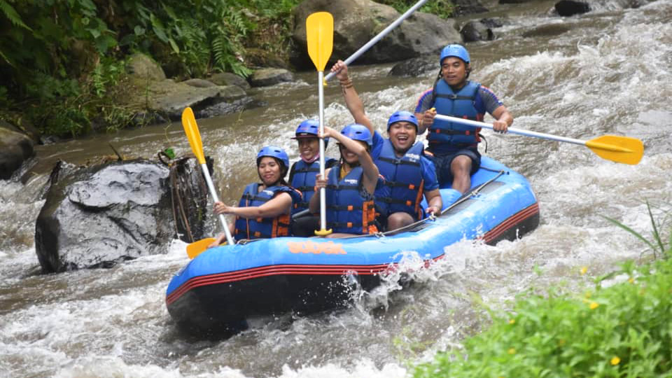 Three women and two men on a raft were smiling and screaming in excitement. Bali White Water Rafting | Bespoke Indonesia Holiday