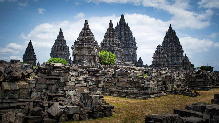 There are 6 towering spires of Hindu temples surrounded by ruins and green vegetations. Indonesia in a Nutshell | Bespoke Indonesia Holiday.
