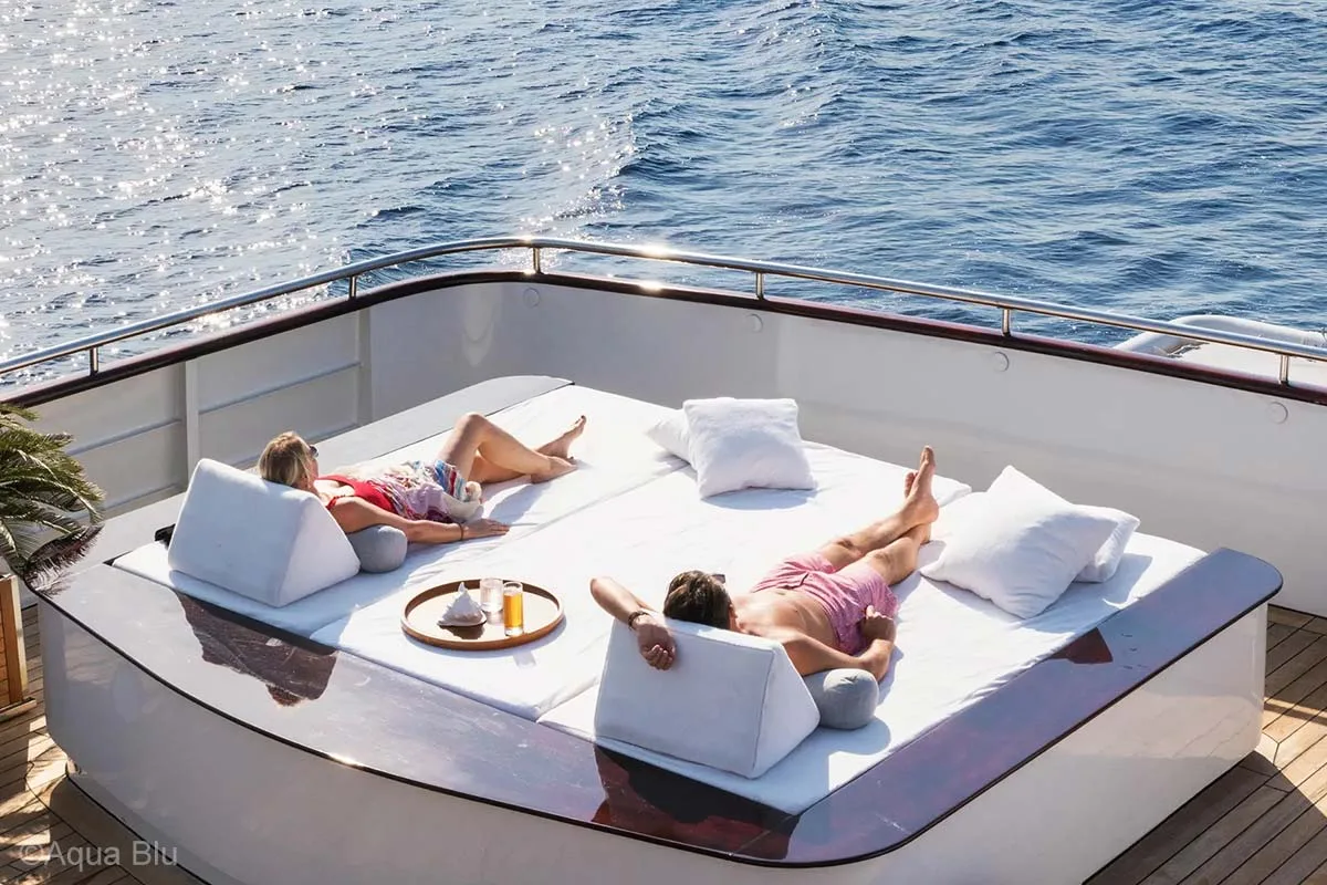 A couple is relaxing on a large sun loungers on a yacht while enjoying the view of the ocean. Aqua Blu. Aqua Blu Yacht. Luxury holidays Indonesia. Luxury Cruise Indonesia. Luxury cruise Raja Ampat. Luxury cruise komodo. Yacht charter Raja Ampat. Yacht charter Indonesia. Yacht charter Komodo. Private cruise Indonesia. Sailing trip Indonesia. Yacht Rental in Indonesia. Yacht charter for a big family in Indonesia. Yacht charter for a big group in Indonesia. Bespoke Indonesia Holiday.