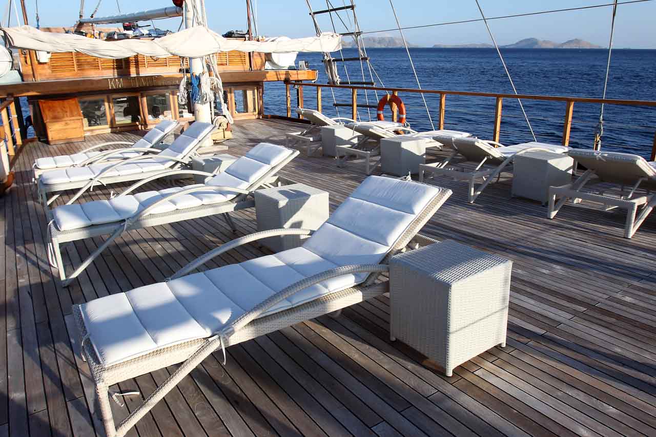 There are four white greyish sun loungers and 4 square rattan tables on a wooden boat. Tiare Cruise. Luxury liveaboard Indonesia. Luxury liveaboard Raja Ampat. Luxury liveaboard Komodo. Diving expeditions Indonesia. Liveaboard tours Indonesia. Yacht charter Indonesia. Yacht charter komodo. Yacht rental Indonesia. Luxury Cruise Indonesia. Luxury Cruise Komodo. Luxury Cruise Raja Ampat. Bespoke Indonesia Holiday.