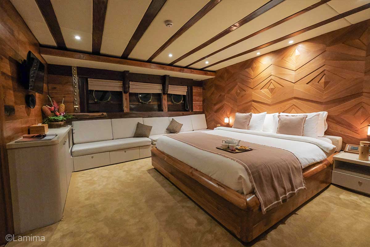 A room with wooden furniture dominated by white and soft brown colour. Lamima Cabin. Lamima Yacht. Luxury holidays Indonesia. Luxury Cruise Indonesia. Yacht charter Indonesia. Private cruise Indonesia. Sailing trip Indonesia. Yacht Rental in Indonesia. Bespoke Indonesia Holiday.